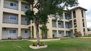 Un immeuble résidentiel à plusieurs étages, doté de balcons, d’une cour intérieure et d’une pelouse bien entretenue.