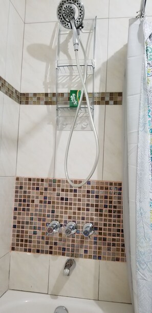 Une salle de bain équipée d’une douche, d’une baignoire et d’un mur carrelé orné d’un motif en mosaïque.