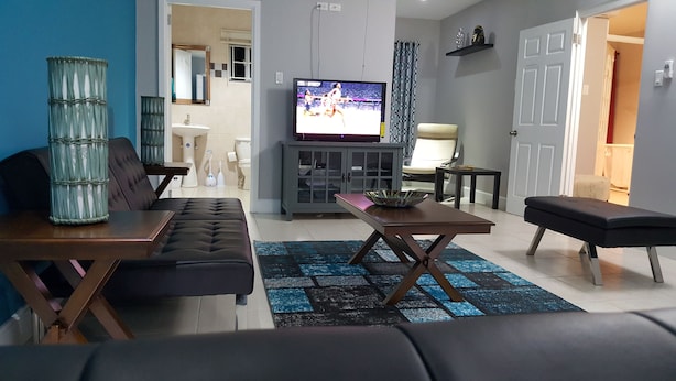Una sala de estar con un sofá, una mesa de centro, un televisor y un aparador.