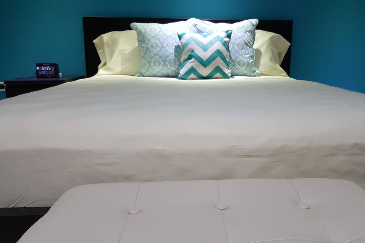 Un lit avec un matelas blanc et une tête de lit agrémentée d’oreillers à motifs.