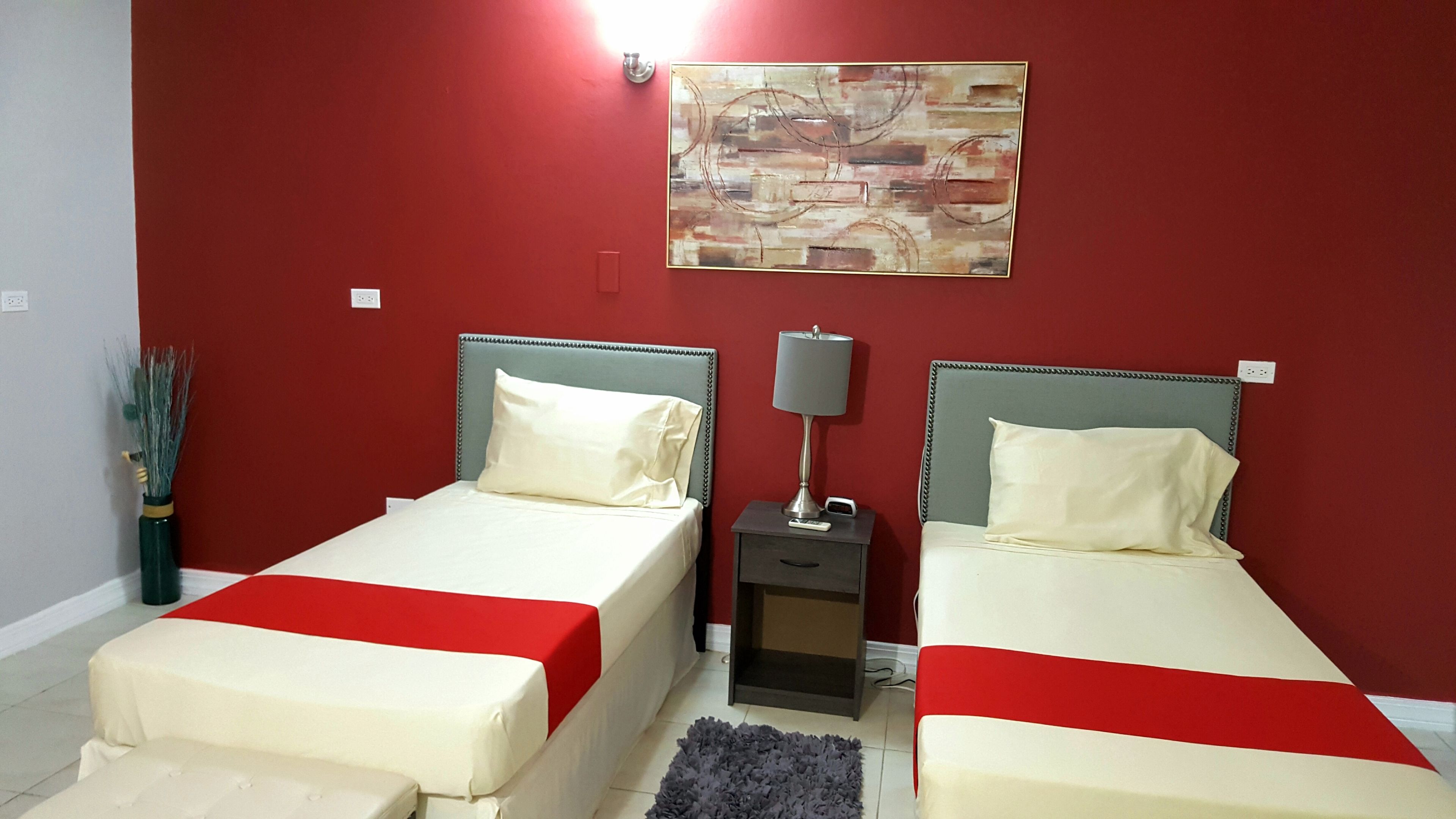 A hotel room with two beds, a nightstand, a lamp, and a wall art piece.