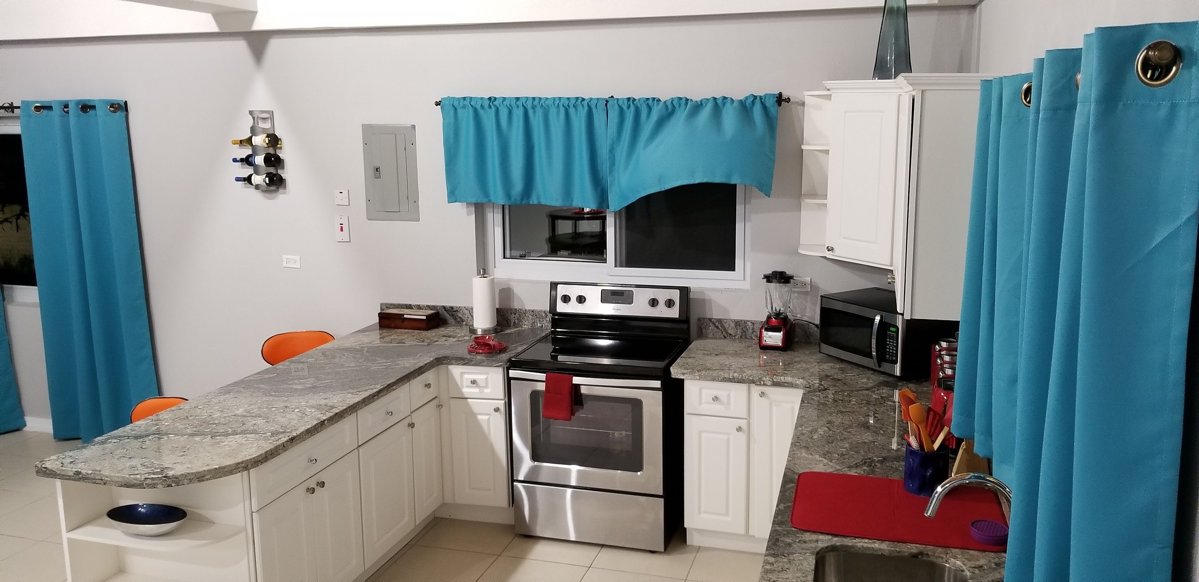 A compact kitchen with white cabinets, a stainless steel oven, a microwave, and a sink.