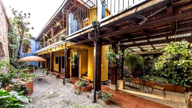 Un patio con suelo de piedra, mobiliario exterior y plantas en macetas.