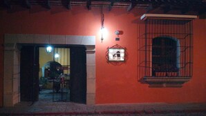 Una entrada a un edificio con un letrero que indica un hotel. Se observa una pequeña ventana con una reja de metal y un letrero sobre ella.