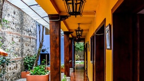 Un pasillo con suelo de baldosas, columnas de madera y faroles colgantes.