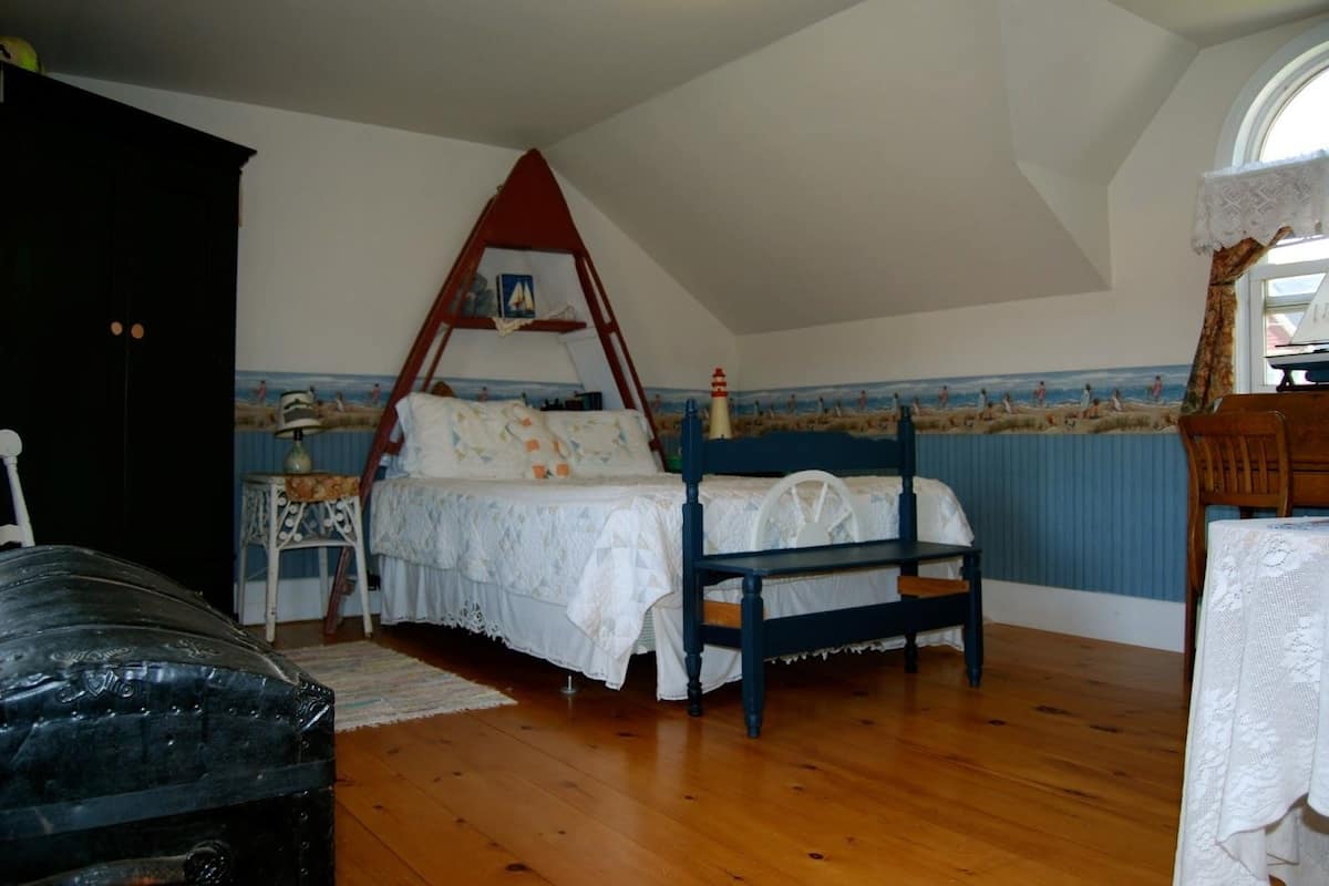 A bedroom with a wooden bed, a small table, and a chair.