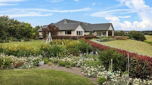 A two-story house with a sloped roof, surrounded by a well-maintained garden with various plants and flowers.