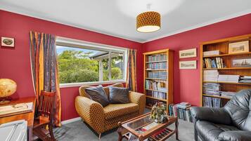 A living room with a red wall, a patterned sofa, a leather armchair, a bookshelf, and a globe on a desk.