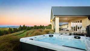 A hot tub with a view of a house and landscape.