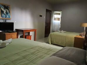 A hotel room with a bed, a desk, a television, and a door. - B n T Inn (Lapu-Lapu)
