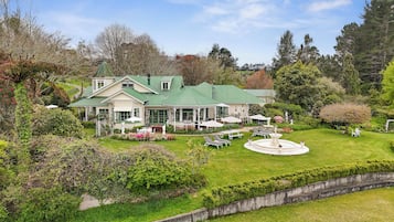 Une grande maison avec un toit végétalisé, un patio couvert et une fontaine circulaire.