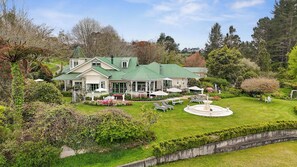 A large house with a green roof, a covered patio, and a circular fountain. - Country Villa Estate (Hamurana)