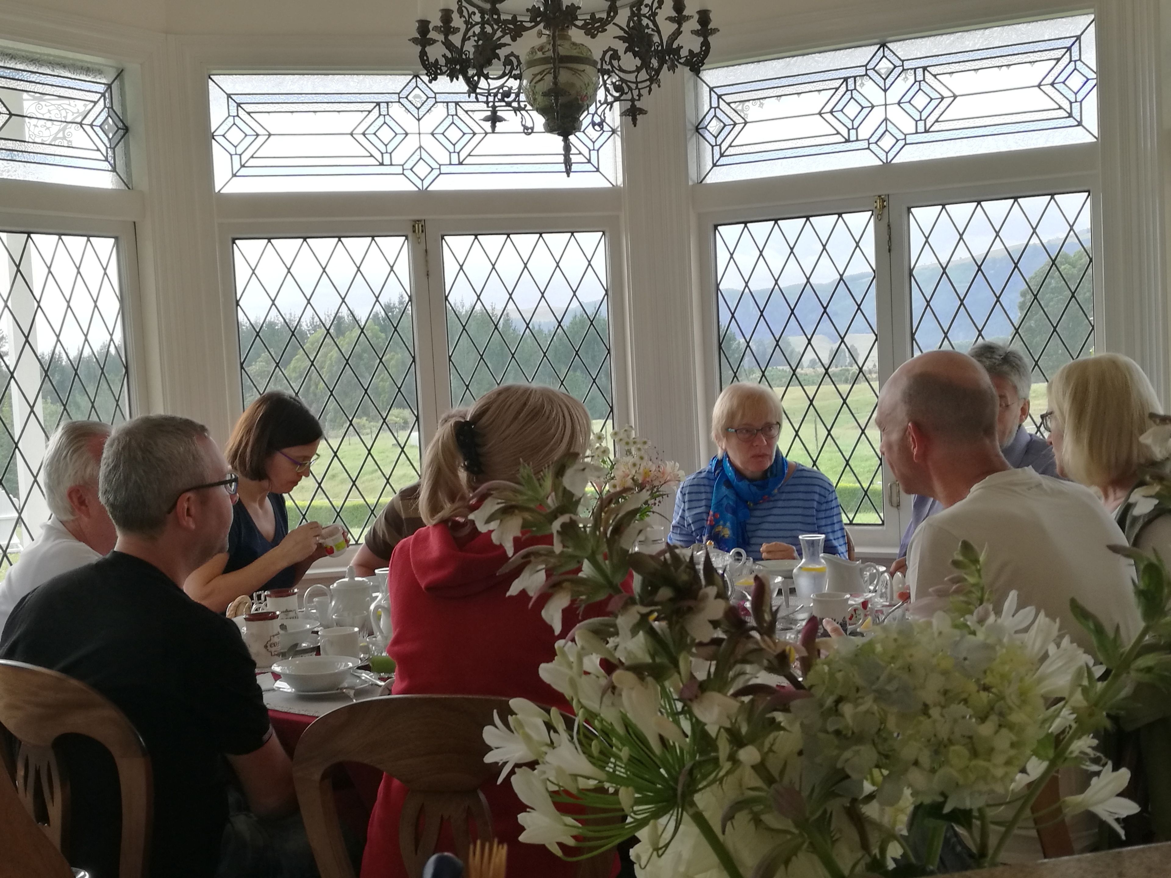 Ein Essbereich mit großen Fenstern, einer Kandelaber und einem für eine Mahlzeit gedeckten Tisch.