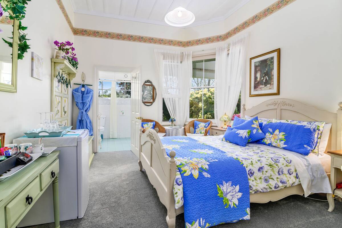 A bedroom with a bed, a desk, a chair, and a window.