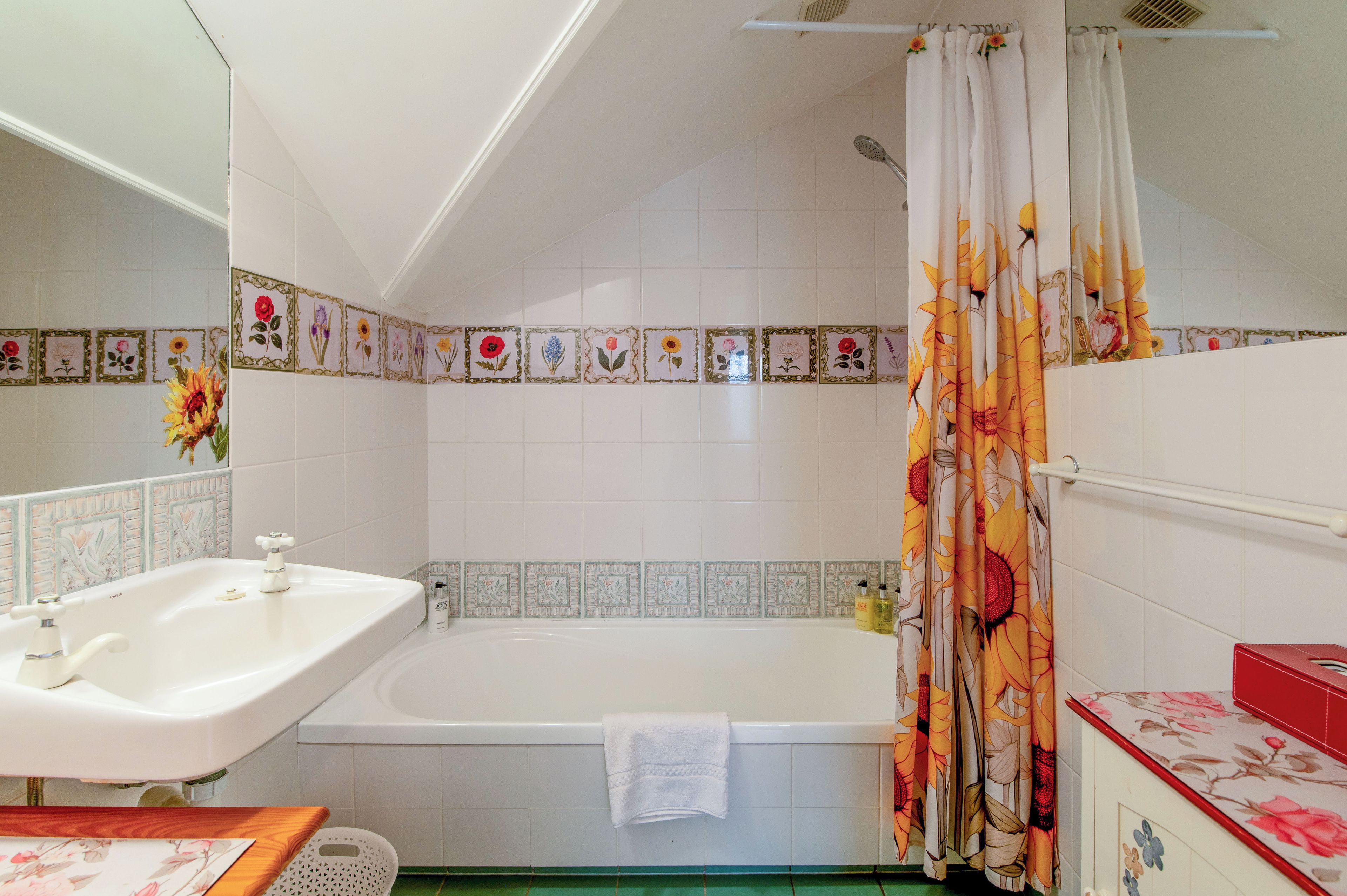 A bathroom with a bathtub, a sink, and a shower curtain with floral patterns.