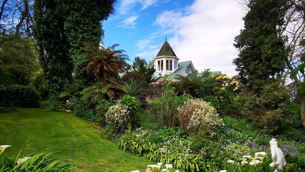 A garden with white calla lilies and a gazebo with a conical roof. - Country Villa Estate (Hamurana)