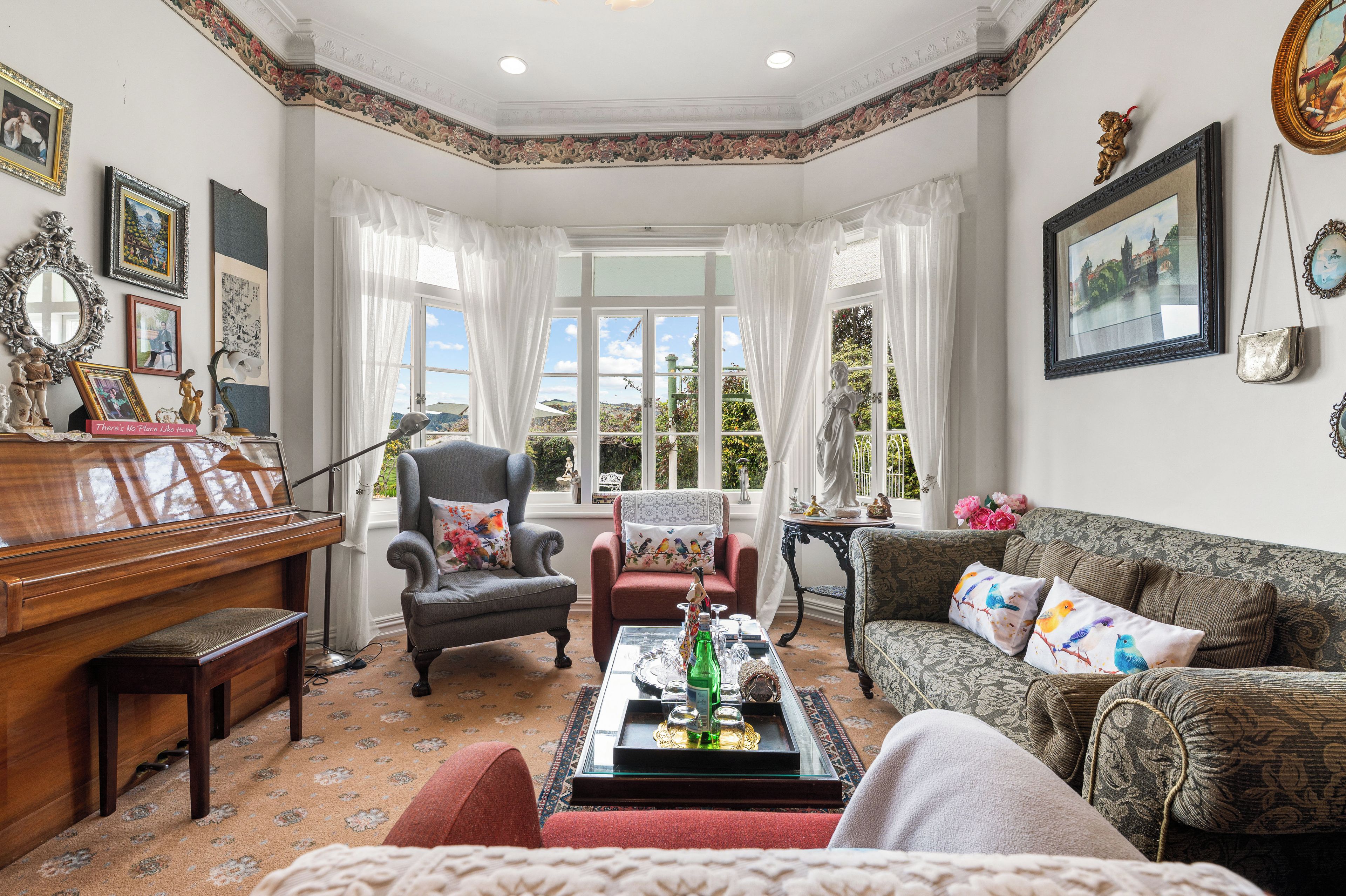A well-furnished living room with a piano, a sofa, a chair, and a table with decorative items.