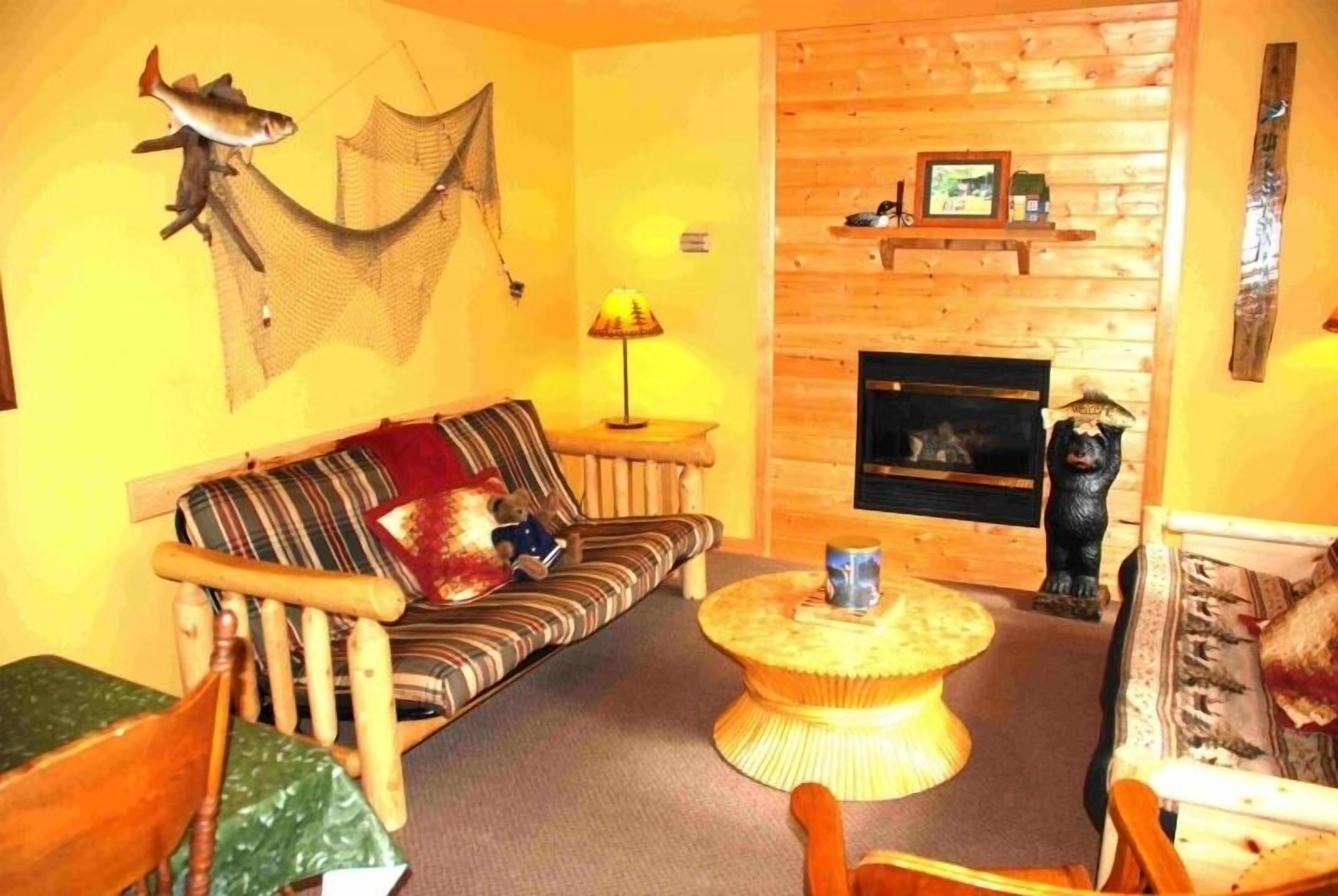 A cozy living room with a wooden sofa, a round coffee table, a fireplace, and a bear statue.