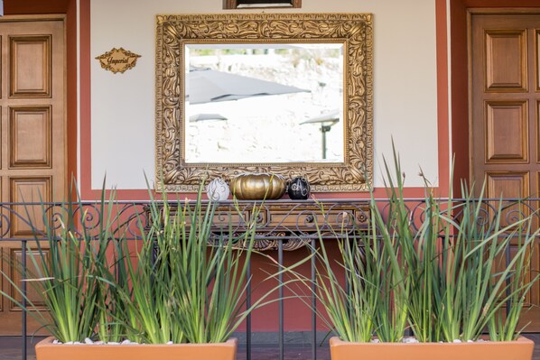 A decorative mirror with ornate gold framing, a small clock, and decorative vases on a mantelpiece.