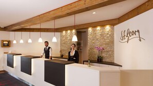 A reception area with a stone wall and a sign that reads "St. Georg." - Hotel St. Georg Gmbh (Bad Aibling)