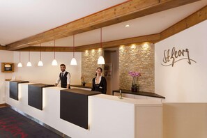 A reception area with a stone wall and a sign that reads "St. Georg." - Hotel St. Georg Gmbh (Bad Aibling)