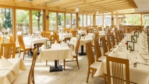 Un restaurante con interiores de madera, ventanas amplias y mesas dispuestas para comer.