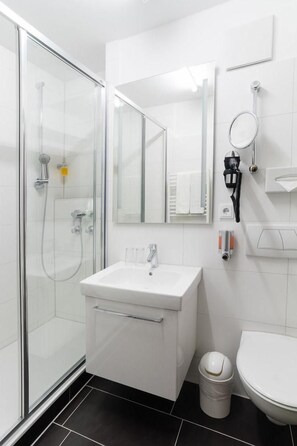 Ein modernes Badezimmer mit Glasdusche, Waschbecken, Spiegel und Toilette.