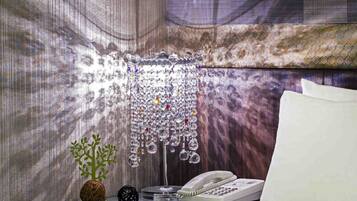 A hotel room with a bed, a bedside table with a telephone, and a decorative hanging light fixture.