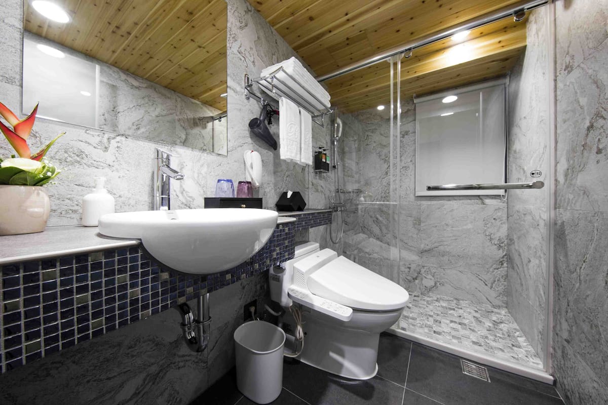 A modern bathroom with a marble sink, toilet, and shower.