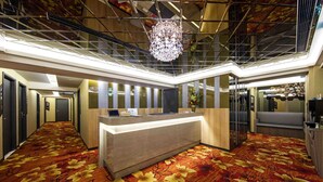 A hotel lobby with a reception desk, a staircase, and a modern chandelier. - Hotel I Journey (Taipei)