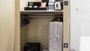 A hotel room with a minibar, a desk with a computer and a flat-screen TV, a suitcase, and a door. - Hotel I Journey (Taipei)