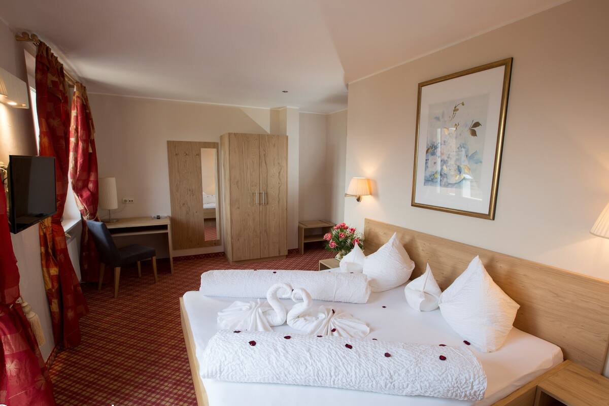 A hotel room with two beds, a desk, a TV, and a wardrobe.
