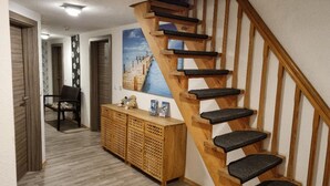 A wooden staircase with black steps leading to a landing area. - Up Diek (Wittmund)