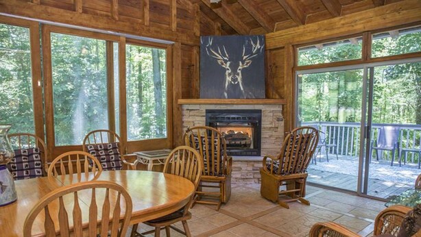A wooden interior with a fireplace, large windows, and outdoor deck. - Brook Trout Inn (Sapphire)