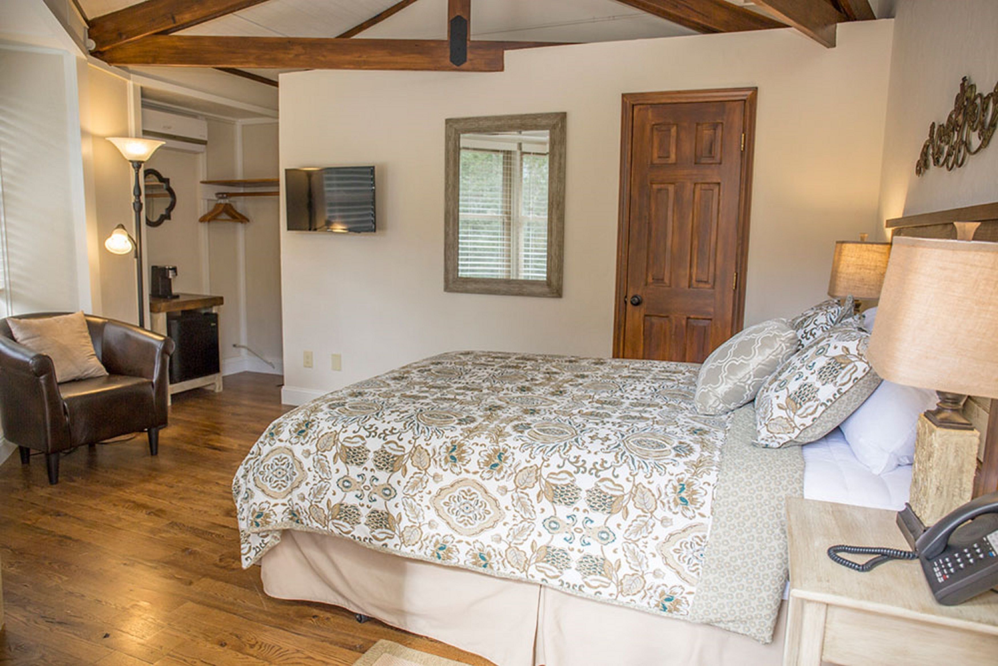 Une chambre à coucher avec un grand lit, une chaise, une table de chevet avec une lampe et une porte en bois.