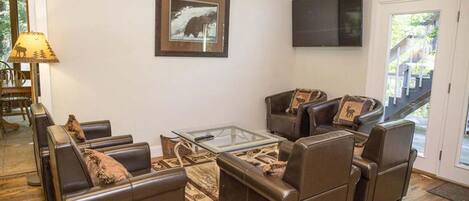 A living room with leather sofas, a glass coffee table, and a framed picture of a bear.