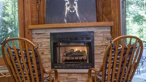 A cozy room with a stone fireplace, two wooden rocking chairs, and a large deer painting on the wall. - Brook Trout Inn (Sapphire)