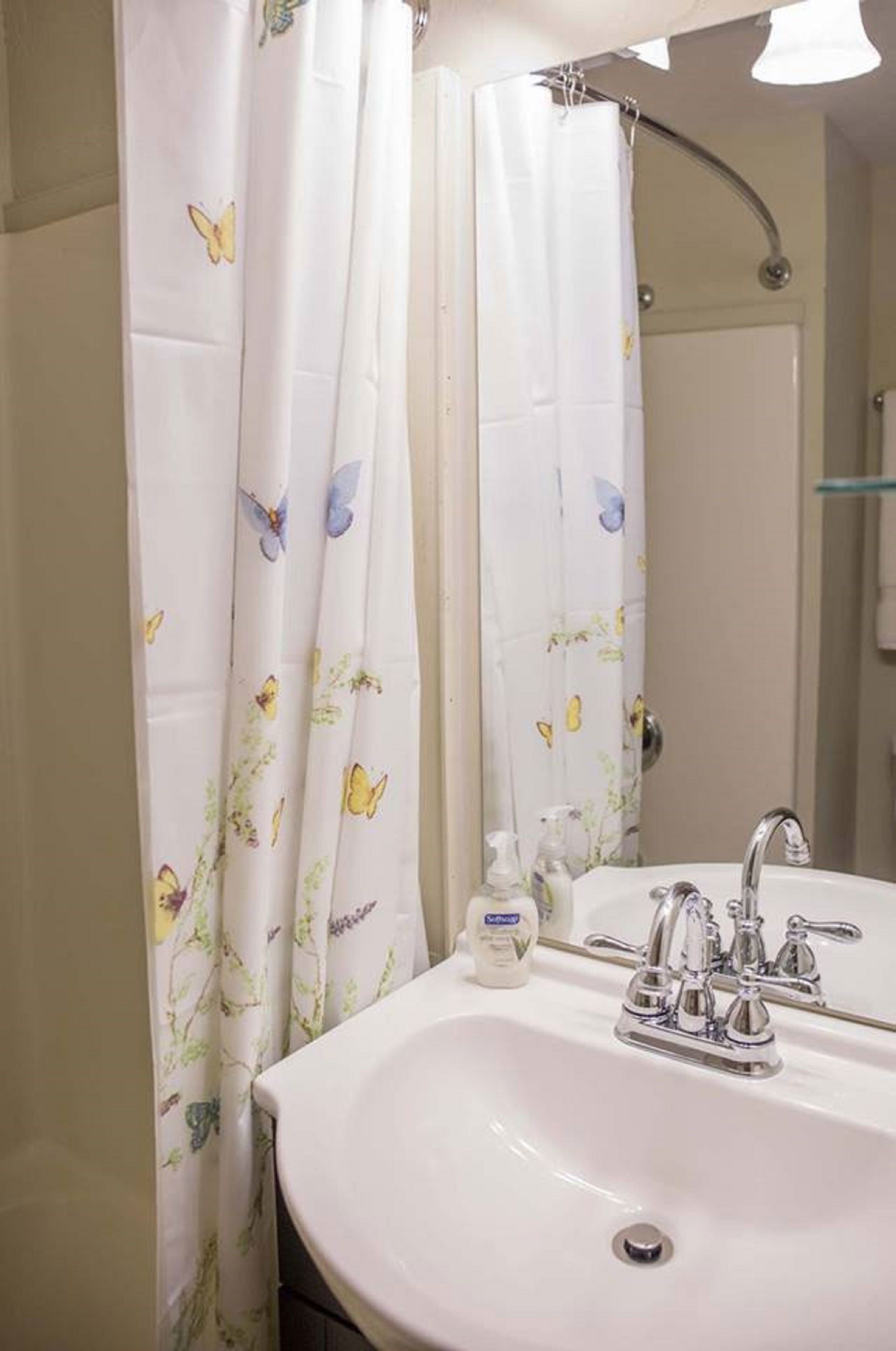 A bathroom with a white sink, a mirror, and a shower curtain with butterfly patterns.