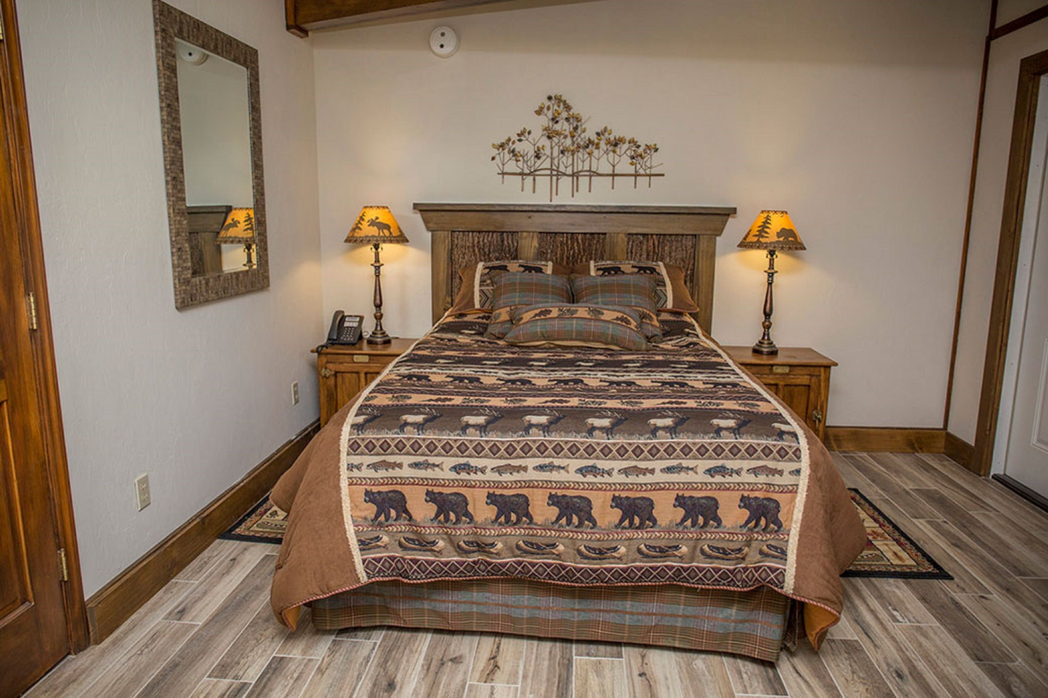 Un dormitorio con una cama grande, dos mesitas de noche con lámparas, un cabecero de madera y un espejo en la pared.