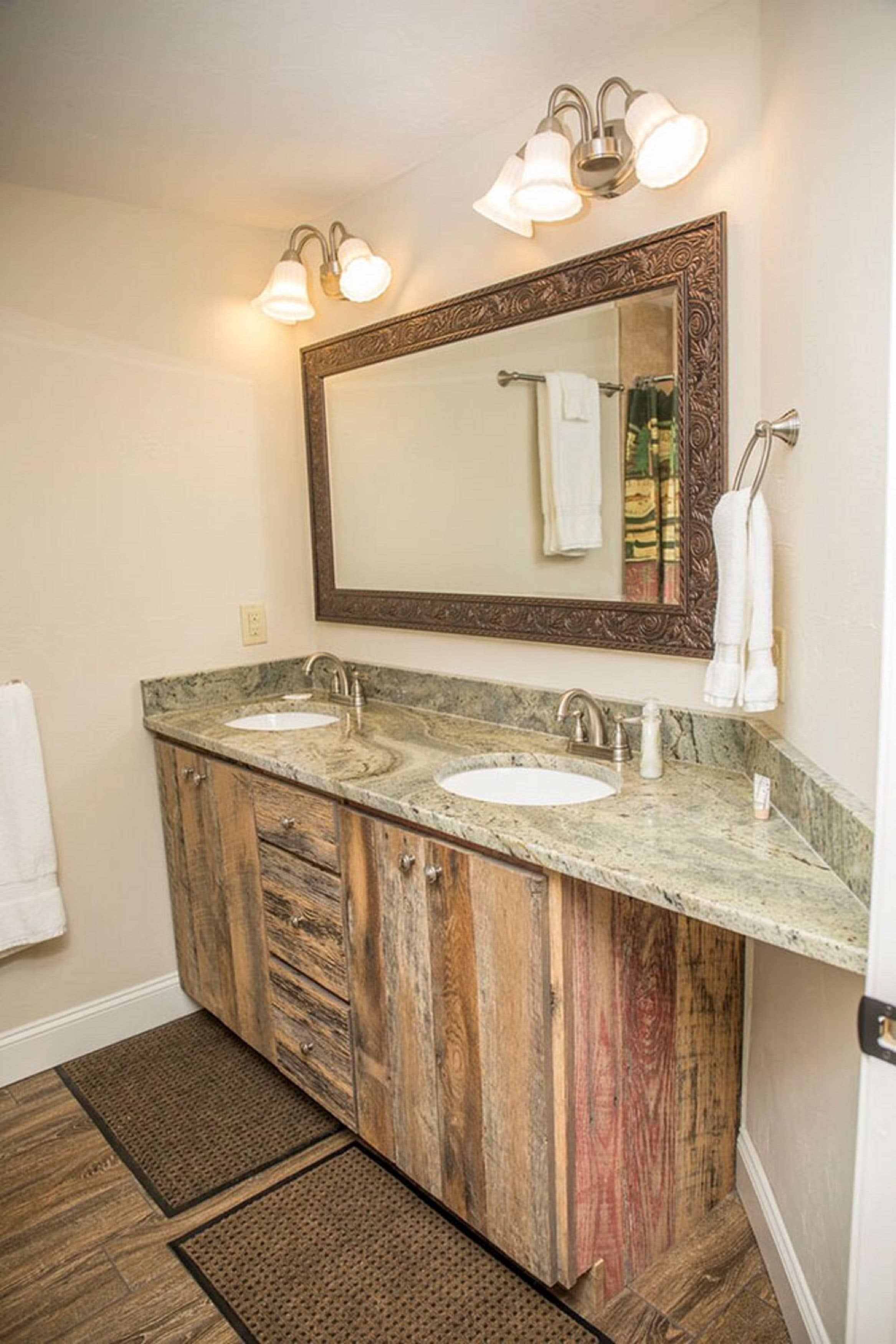 A bathroom with two sinks, wooden cabinets, a large mirror, and wall-mounted lights.