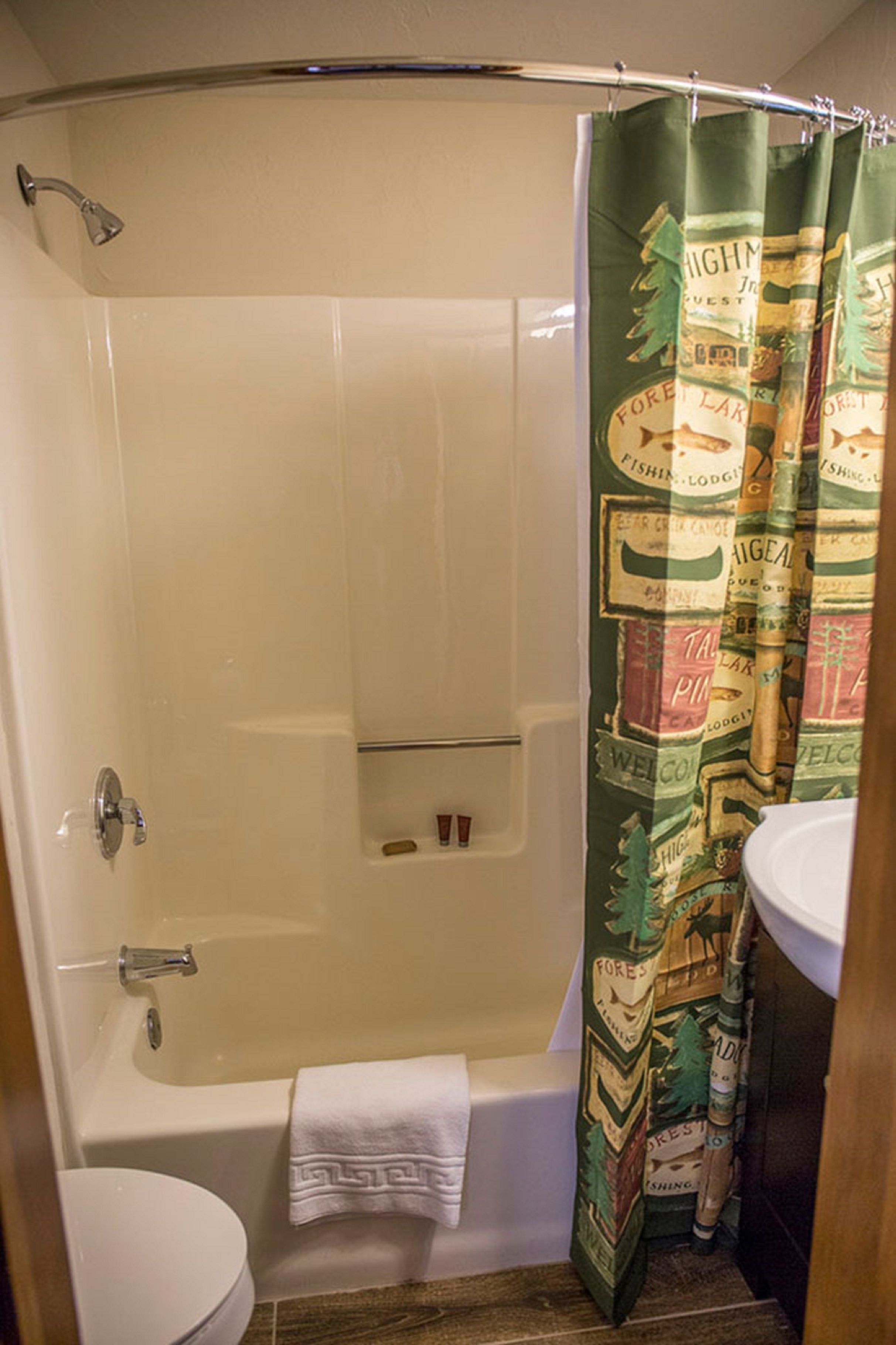 A bathroom with a shower curtain, a bathtub, and a toilet.