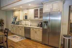 A modern kitchen with stainless steel appliances, wooden cabinets, and a tiled backsplash.