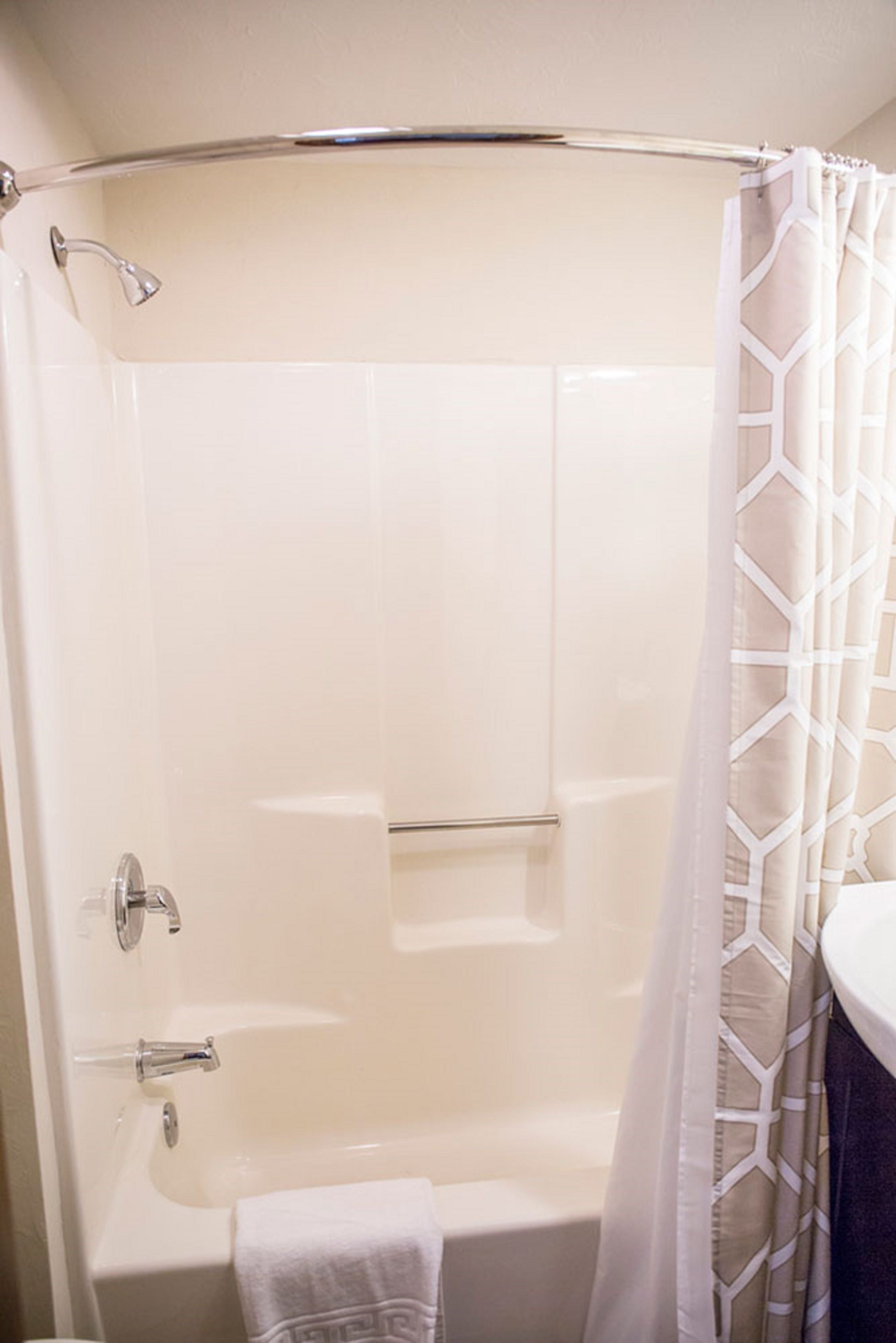 A shower with a glass door, a towel rack, and a shower curtain.
