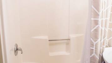 A shower with a glass door, a towel rack, and a shower curtain.