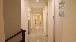 Pasillo de hotel con indicaciones, barandilla y suelo de baldosas.