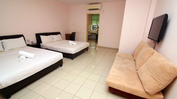 A hotel room with two beds, a sofa, a TV, and a bathroom visible through an open door.