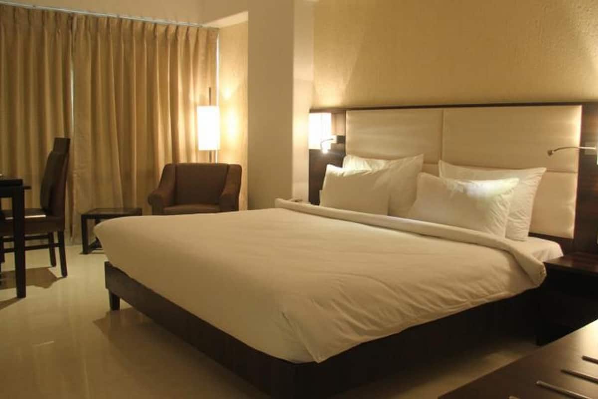 Una habitación de hotel con una cama grande, una silla, un escritorio y una mesita de noche.