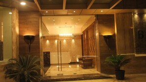 A reception area with a glass partition, wooden walls, and a chandelier. - Beacon T2 Mumbai (Mumbai)
