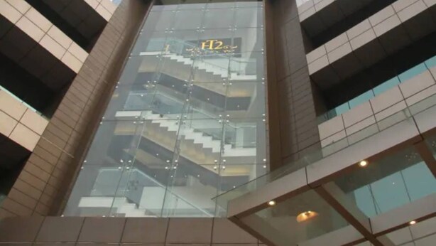 A modern building with a glass facade, a visible staircase, and a sign with 'H2' on it. - Beacon T2 Mumbai (Mumbai)
