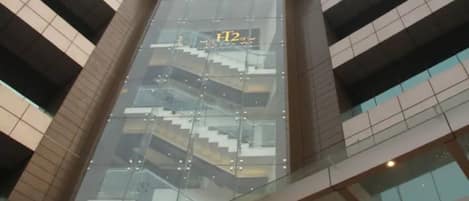 A modern building with a glass facade, a visible staircase, and a sign with 'H2' on it.